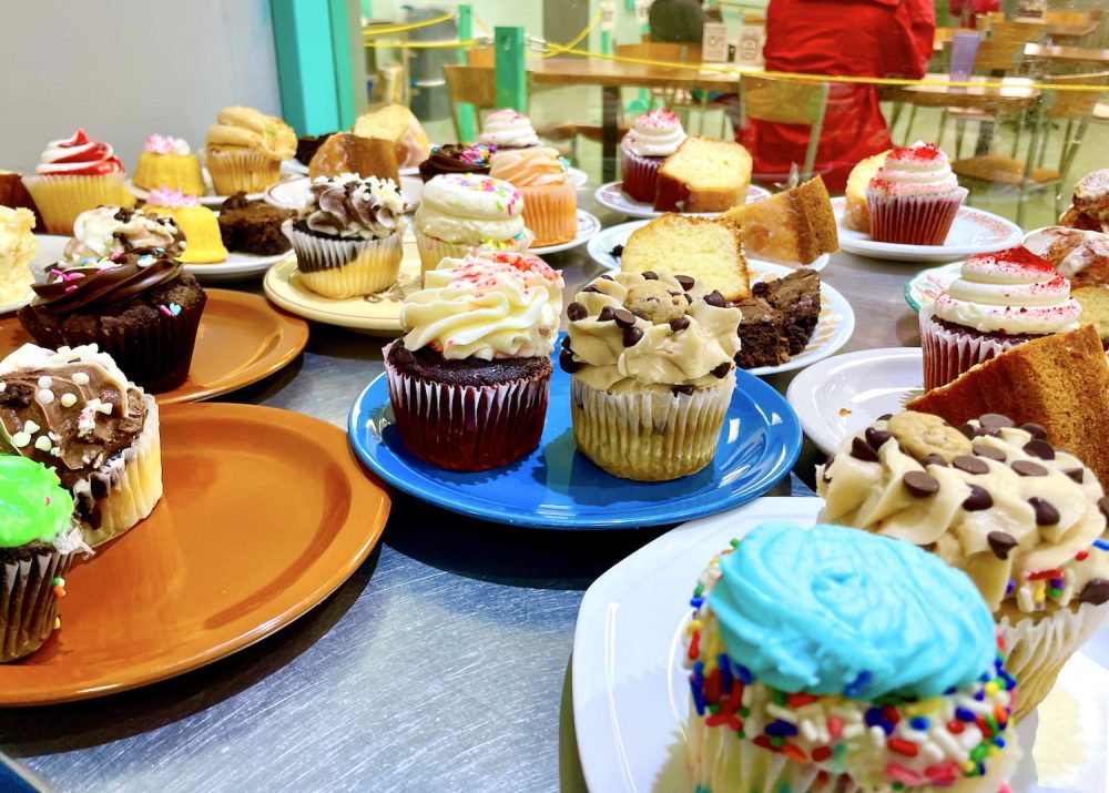about a dozen plates with really beautifully decorated cupcakes on them, with our dining room in the background