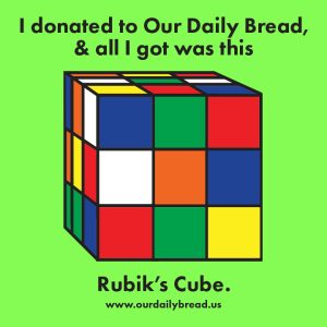 An illustration of an unsolved Rubik’s Cube. The background color is lime green. Text above and below reads I donated to our daily bread and all I got was this Rubick’s Cube. www.ourdailybread.us