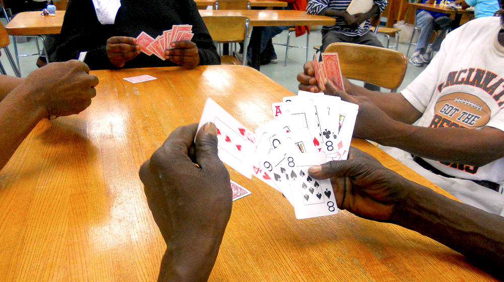 closeup of four sets of hands playing cards at a table