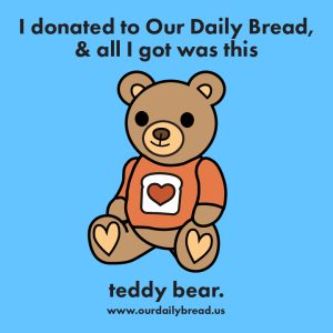 an illustration of a brown teddy bear wearing a little light reddish orange t shirt with the white slice of bread with a red heart in the center from our logo on it. The background color is light blue. Text above and below reads I donated to Our Daily Bread and all I got was this teddy bear www.ourdailybread.us